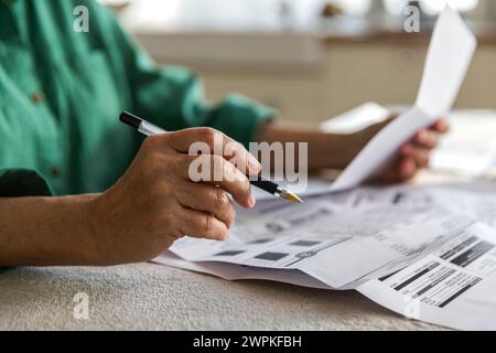 Ältere Frau Hand mit Stift auf Papierkram mit Rechnungen und Quittungen Stockfoto