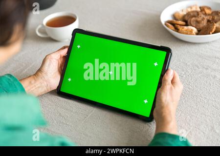 Tablette mit grünem Chromakey-Display in der Hand älterer Frauen Stockfoto