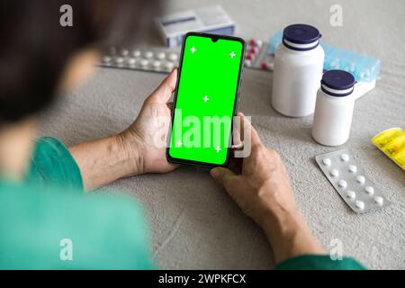 Mobiler Green Screen bei älteren Frauen Hand auf Tisch mit Medikamenten Stockfoto