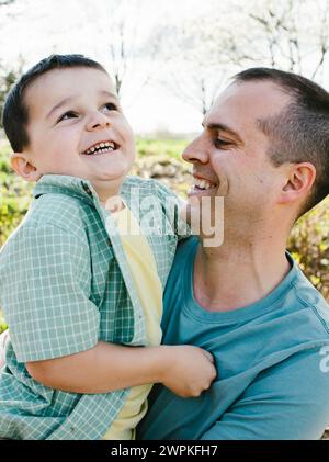 Lachender und lächelnder Vater, der den Sohn im Frühling zusammenhält Stockfoto