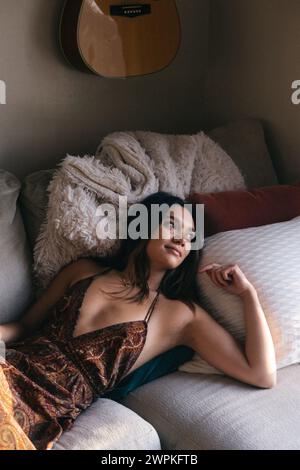 Multirassische Frau, die auf der Couch liegt und aus dem Fenster in San Diego starrt Stockfoto