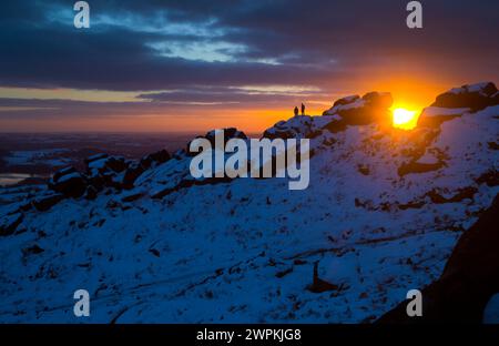 02/15 ohne Ende der Eiszeit, die das Land packt, stehen zwei Bergsteiger auf Felsen, um einen beeindruckenden Sonnenuntergang zu bestaunen Stockfoto