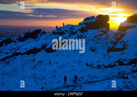 02/15 ohne Ende der Eiszeit, die das Land packt, stehen zwei Bergsteiger auf Felsen, um einen beeindruckenden Sonnenuntergang zu bestaunen Stockfoto