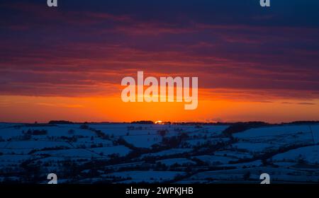 02/15 da kein Ende in Sicht ist für die eisigen Bedingungen, die das Land ergreifen, signalisiert ein beeindruckender Sonnenuntergang den Beginn einer weiteren kalten Nacht über T Stockfoto