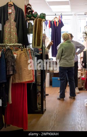 Leute unterhalten sich in einem Wohltätigkeitsladen in Newquay in Cornwall, Großbritannien. Stockfoto