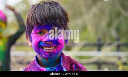 Glückliche indische Freunde oder Kinder, die das Hindufest von Holi feiern, indem sie sich gegenseitig Farben auftragen, beste Freunde. Weibliche Geschwister, die einen Teller halten Stockfoto