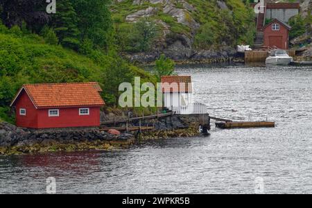 Ein kleines norwegisches Holzboot mit JettyÕs befindet sich an einem langweiligen Tag im Juni in einem versteckten Inlet of Cove am felsigen Ufer des Bergen Fjords. Stockfoto