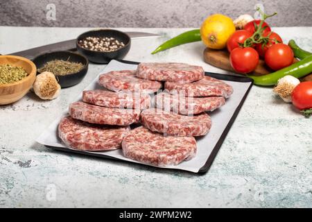 Hamburger Patty. Fleischerprodukte. Rohe Hamburgerpasteten mit Gelatine auf Steingrund Stockfoto