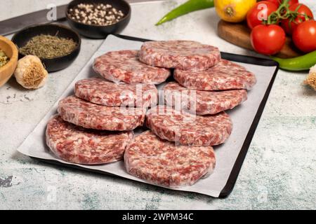 Hamburger Patty. Fleischerprodukte. Rohe Hamburgerpasteten mit Gelatine auf Steingrund Stockfoto