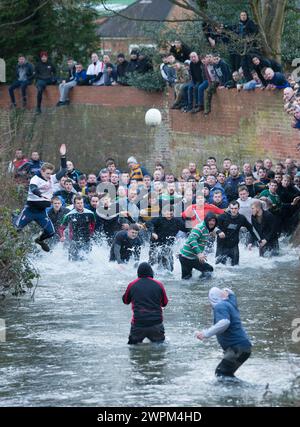 02/16 Spieler jagen den Ball durch Henmore Brook, während das Royal Shrovetide Football Match durch die Stadt Ashbourne in Derbyshire ausgetragen wird. U' Stockfoto