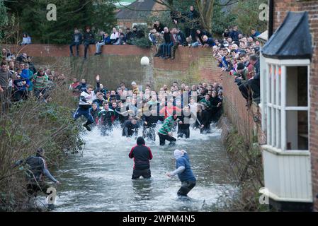 02/16 Spieler jagen den Ball durch Henmore Brook, während das Royal Shrovetide Football Match durch die Stadt Ashbourne in Derbyshire ausgetragen wird. U' Stockfoto