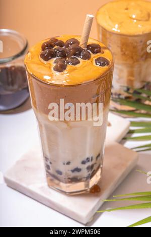 Boba dalgona Kaffee. Trendiges asiatisches Latte-Morgengetränk mit Instant-Kaffee und Tapioka-Perlkugeln, thailändisches Schaumcocktail-Glas im Sommer in der Sonne Stockfoto