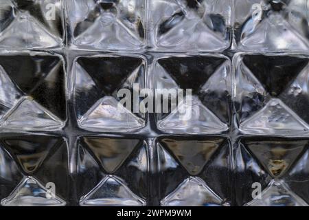 Detail der quadratischen Sechsecke aus Glas, die in dunkler horizontaler Richtung beleuchtet sind Stockfoto