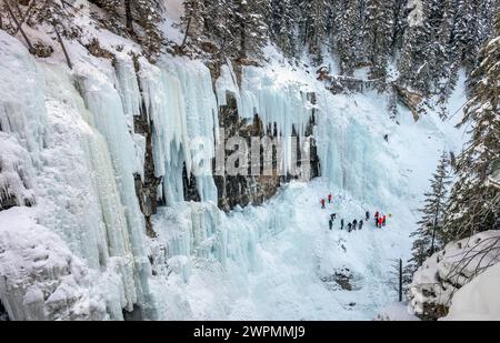 Weit entfernte, nicht erkennbare Eiskletterer an den gefrorenen Upper Falls am Johnston Canyon im Banff National Park, Alberta, Kanada Stockfoto