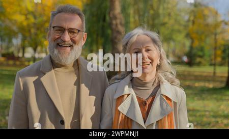 Porträt eines glücklichen, reiferen Paares lächelnd im Herbstpark fröhlicher alter Mann, der zusammen für die Kamera in der Natur posiert eleganter älterer Ehemann Stockfoto