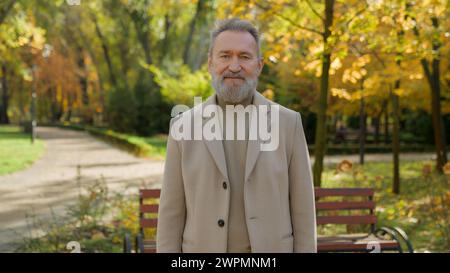 Ältere grauhaarige männliche reife 60er Jahre Mann im Herbst Park Gasse im Freien alter Senior Gentleman gesundes lächelndes Gesicht glückliches Porträt einzelner Rentner Stockfoto