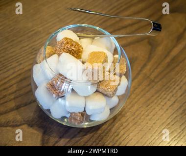 Glas Zuckerschale mit normalem Zucker und Rohrzucker auf dem Tisch Stockfoto