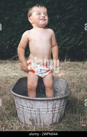 Kleiner Junge chillt in einer kleinen Retro-Blechbadewanne Stockfoto