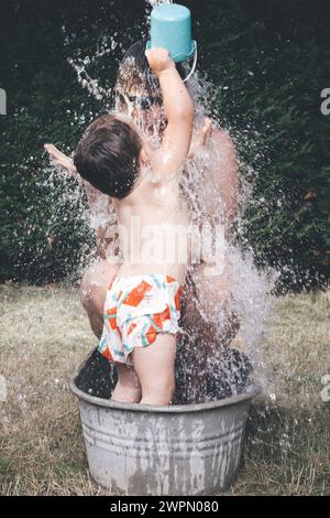 Vater und Sohn chillen in einer kleinen Retro-Blechbadewanne Stockfoto