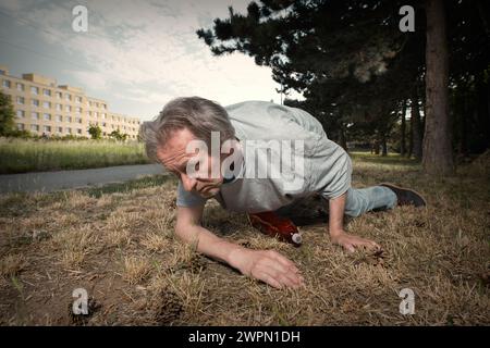 Der süchtige alte Mann betrunken im Sommer Stadtpark unfähig zu laufen Stockfoto