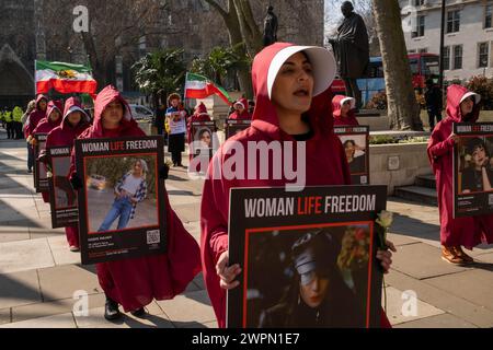 London, UK, 8. März 2024, iranische Frauen in Handmädchen-Tale-Kostümen gehen vom Parlamentsplatz zur iranischen Botschaft in Kensington. Sie fahren durch das Zentrum Londons und halten an mehreren bekannten Sehenswürdigkeiten, darunter Downing Street und Trafalgar Square. Die Frauengruppe hofft, die Aufmerksamkeit auf den Missbrauch der Menschenrechte im Iran zu lenken. Kredit: James Willoughby Stockfoto