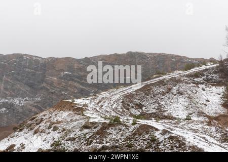 Blick auf Steinbruch im Winter mit Schnee. Keine sichtbaren Personen. Eine kurvenreiche Straße führt einen Hügel hinauf Stockfoto