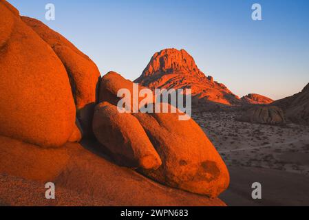 Spitzkoppe im warmen Sonnenaufgangslicht mit Felsformationen im Vordergrund in Namibia, Afrika Stockfoto