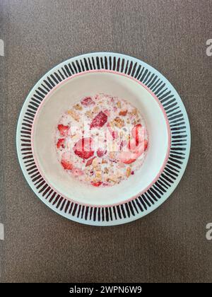 Getrocknete rote Erdbeerscheiben in Müsli mit Milch in einer Schüssel Stockfoto