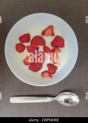 Frische rote Beeren serviert mit natürlichem Joghurt in einer weißen Schüssel zum Frühstück Stockfoto