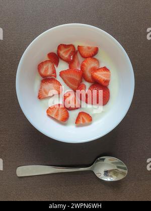 Frische rote Beeren serviert mit natürlichem Joghurt in einer weißen Schüssel zum Frühstück Stockfoto