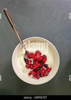 Frische rote Beeren mit natürlichem Joghurt in einer weißen Schüssel zum Frühstück Stockfoto