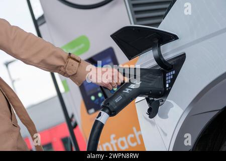 Frau, die ein Elektroauto im Schnellladepark in Kamen, Nordrhein-Westfalen, Deutschland auflädt Stockfoto