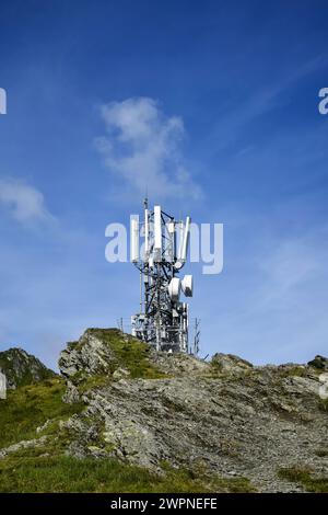 Metallturm mit verschiedenen Telekommunikationsantennen auf einem Berg, vor blauem Himmel, im Frühjahr. Sicherstellung des Betriebs von Stockfoto