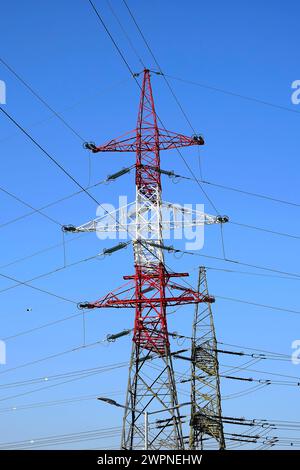 Metallische Pylonen von Hochspannungsleitungen vor blauem Himmel. Der Begriff der Energie, Transport elektrischer Energie. Ansicht von unten. Selektiver Fokus Stockfoto