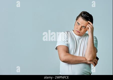 Ein Mann schaut auf den Telefonbildschirm auf grauem Hintergrund Stockfoto