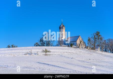 Deutschland, Bayern, Tölzer Land, Münsing, Landkreis Holzhausen, Winterlandschaft mit Pfarrkirche St. Johann Baptist Stockfoto