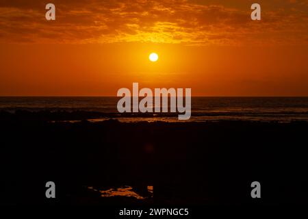 Ein feuriger Sonnenuntergang beendet einen angenehmen Sommertag an der Küste. Widemouth Bay, Cornwall Stockfoto