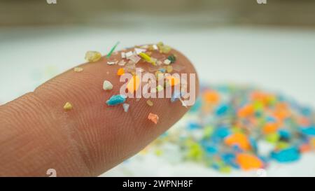 Makroaufnahme von Mikroplastik am menschlichen Finger. Das Konzept der plastischen Verschmutzung mit Nanoplasten. Weicher Fokus auf Mikroplastikpartikeln Stockfoto