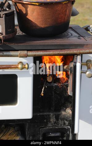 Holzofen in einer Küche mit Kamin und einem Kupfertopf auf der Oberseite zum Aufwärmen für die Zubereitung von Polenta, einem typisch norditalienischen Essen mit Yello Stockfoto