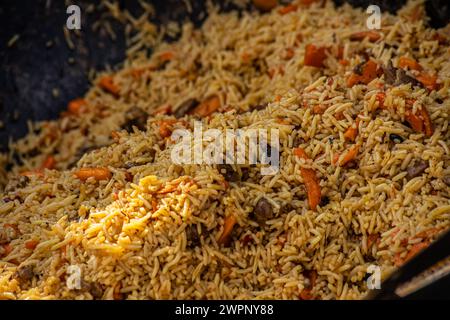 Heißer Pilaf in großem Kessel im Freien. Traditionelle orientalische Küche. Street Food Konzept. Nahaufnahme Stockfoto