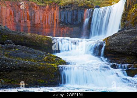 Slaidufoss (Veil Falls) fällt über Basaltsäulen, die durch Eisenoxid rot gefärbt sind, im kleinen Fluss Laugara bei Laugarfell nahe Mount Snaefell im Nordosten Islands. Stockfoto