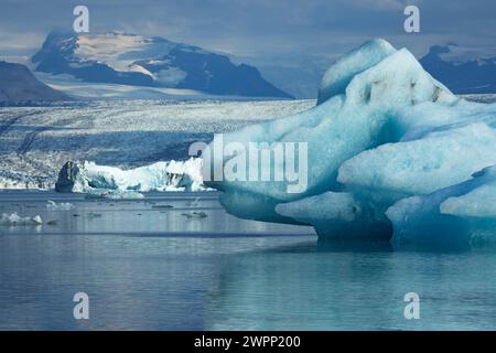 Glitzernde türkisfarbene Eisberge auf dem Gletschersee Joekulsarlon vor den Esjufjell Bergen. Stockfoto