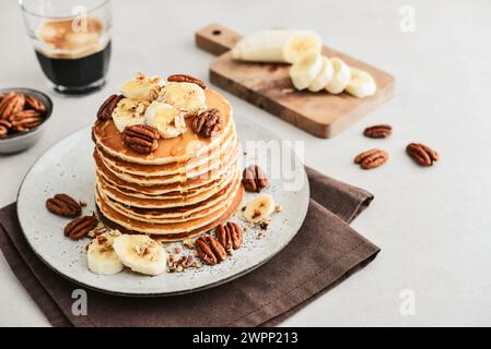 Teller mit Ahorn-Pekannkuchen mit frischen Bananen und Kaffee im Hintergrund. Stockfoto