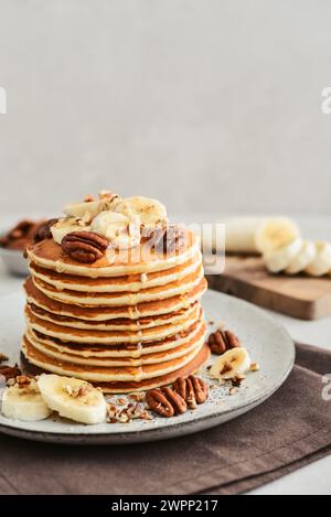 Teller mit Ahorn-Pekannkuchen mit frischen Bananen und Kaffee im Hintergrund. Stockfoto