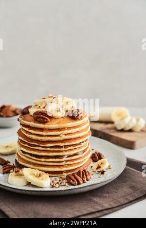 Teller mit Ahorn-Pekannkuchen mit frischen Bananen und Kaffee im Hintergrund. Stockfoto