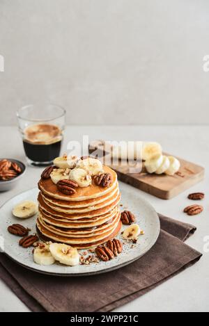 Teller mit Ahorn-Pekannkuchen mit frischen Bananen und Kaffee im Hintergrund. Stockfoto