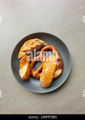 Übrig gebliebenes Brot und Backwaren wie Brezeln und Brezelstangen liegen auf einem grauen Teller Stockfoto