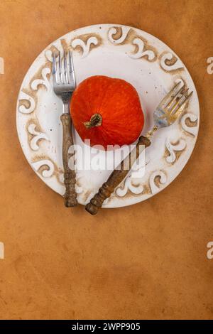 Herbstliches Stillleben, Kürbis auf einem Teller mit zwei Gabeln Stockfoto
