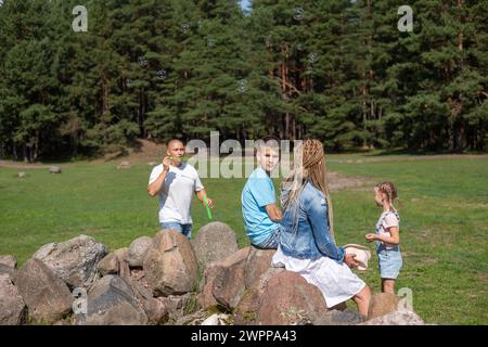 Eine Familie genießt ein Outdoor-Abenteuer in einer Kiefernwaldlichtung, dieses Bild verkörpert den Geist des Kinderspiels und der Familienspaß in der Natur. Stockfoto