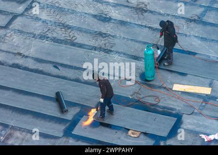 Wien, Bauarbeiter, die 22 mit Bitumenmembranen Abdichtungsarbeiten an einer Gebäudedecke durchführen. Donaustadt, Wien, Österreich Stockfoto